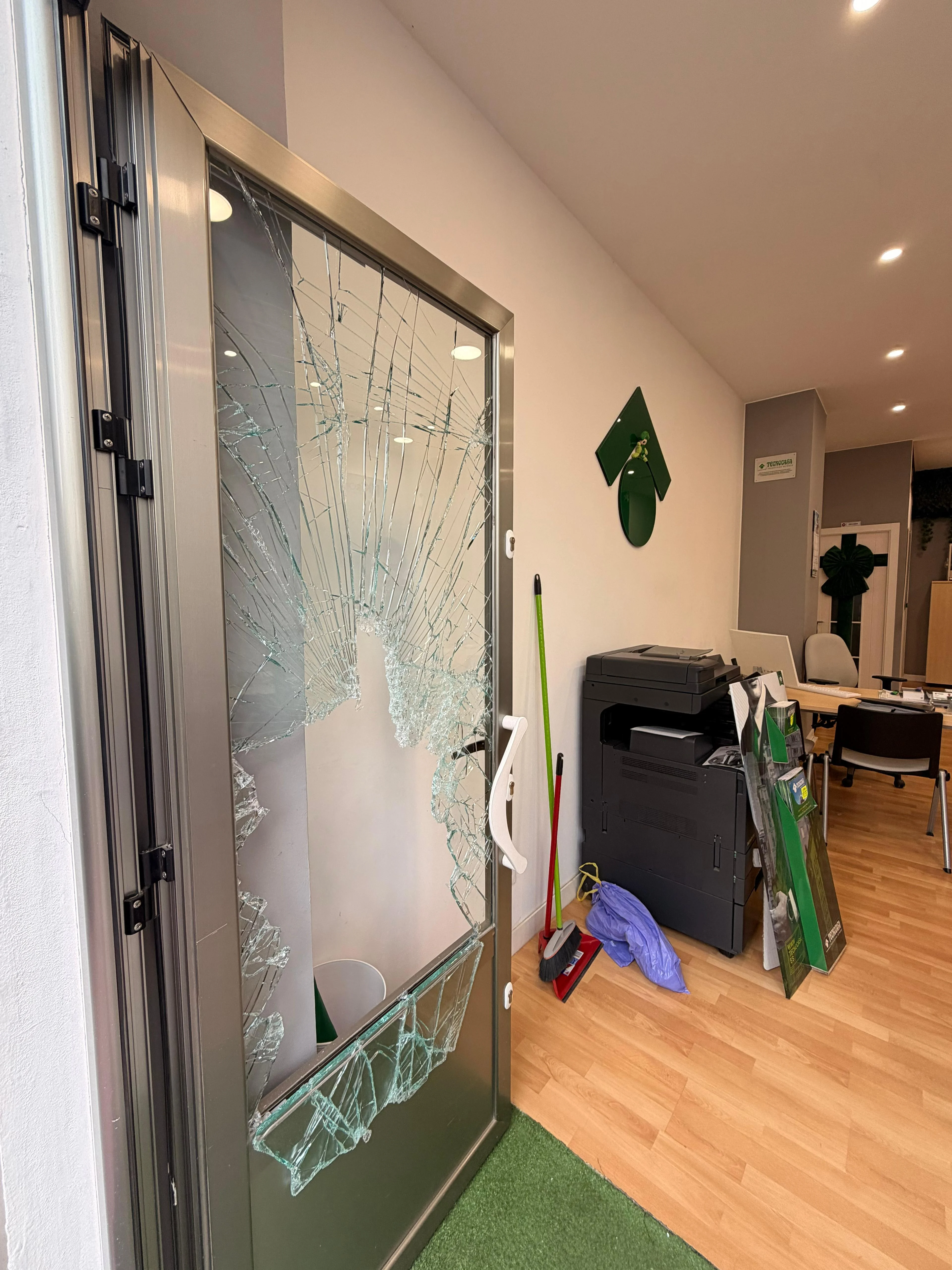 Antes: puerta de cristal rota, abierta hacia el interior de la inmobiliaria