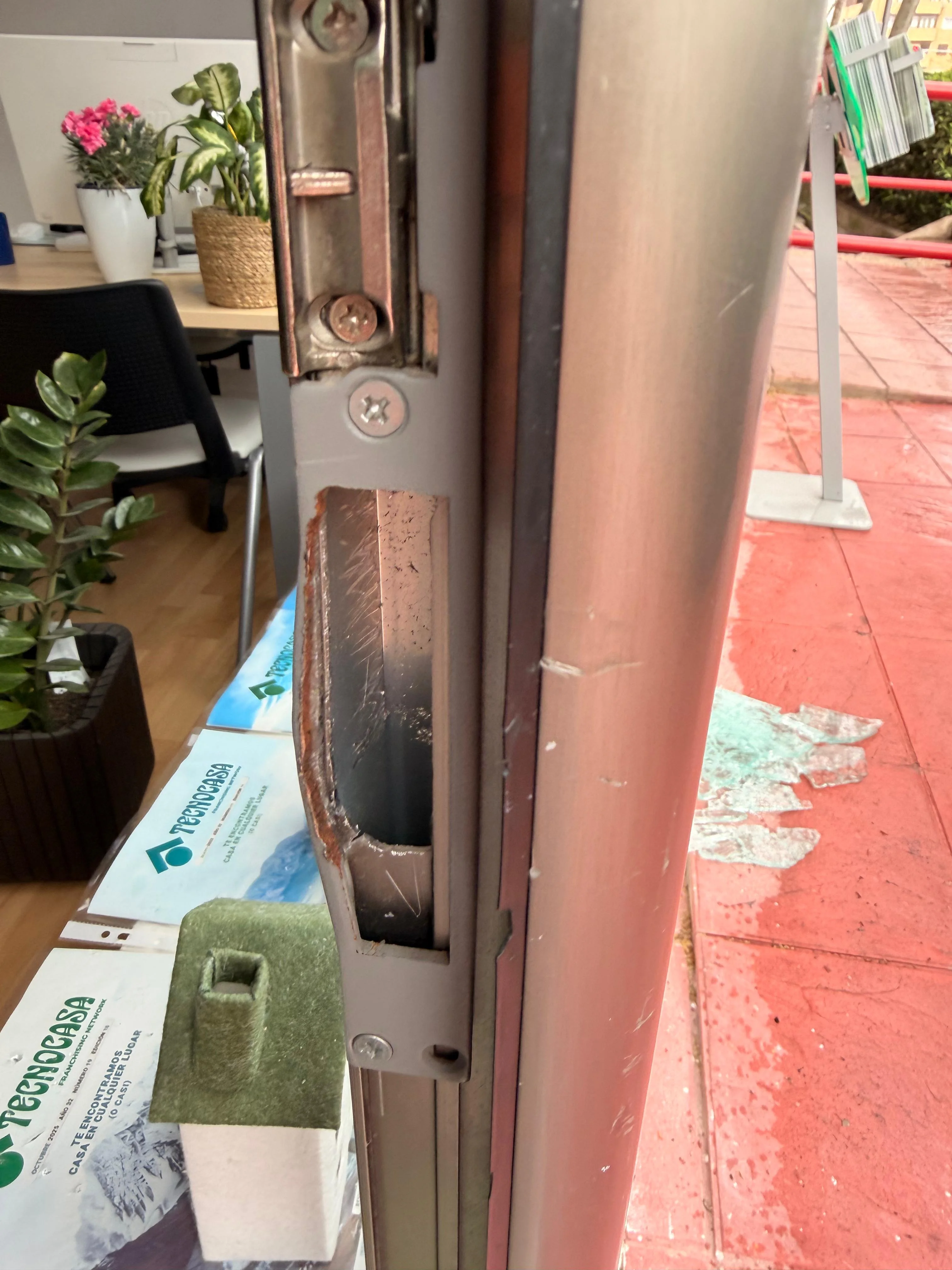 Antes (frontal): cerradero y zona de cierre del marco doblados en puerta de cristal tras intento de robo